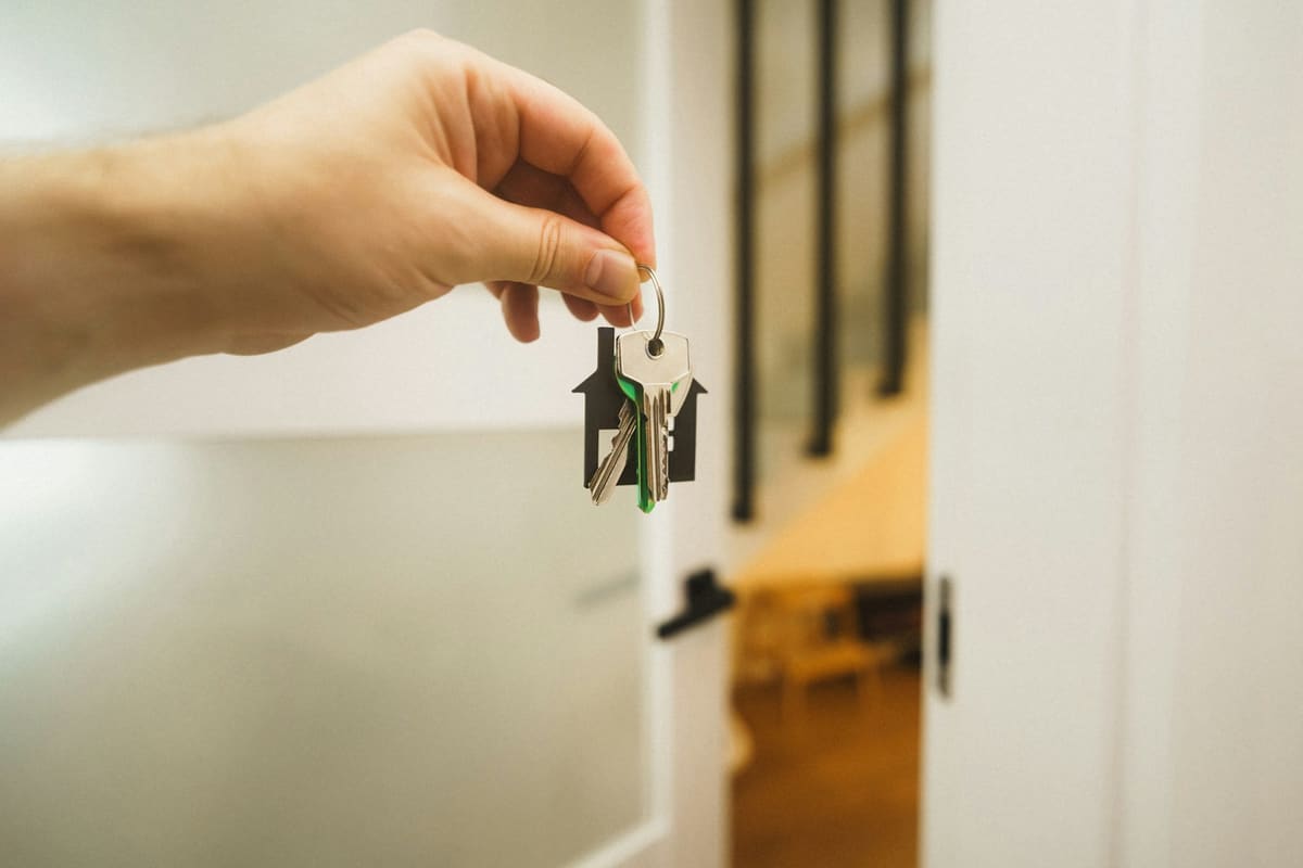 A hand holding a house key at an open door